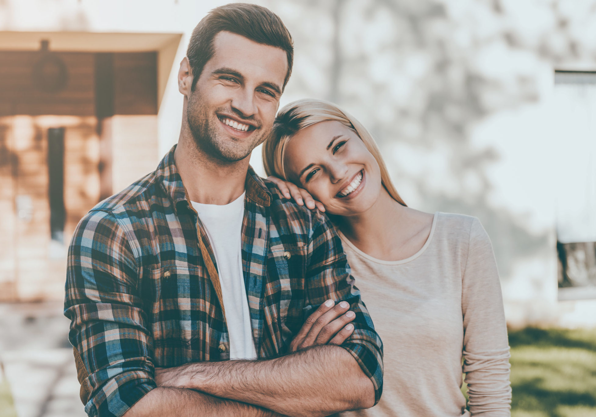 Happy loving couple. Happy young couple bonding to each other and smiling while standing against their new house